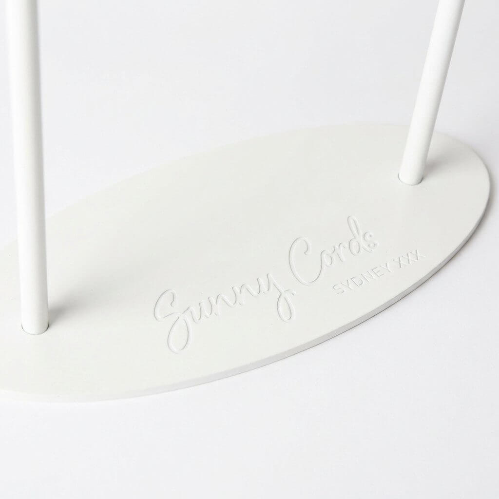 Close-up of a cream metal jewelry stand featuring a precision etching LOGO on a stable oval base