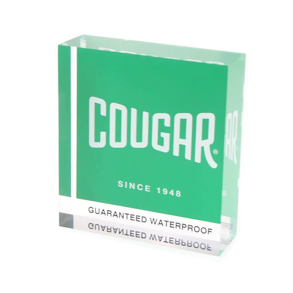 Clear custom acrylic paperweight with 1.5-inch thickness featuring a white logo reverse-printed on a green background.