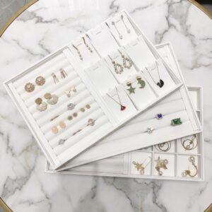 Custom jewelry display trays in white PU leather with 24 compartments and a gold-stamped brand logo for retail showrooms.