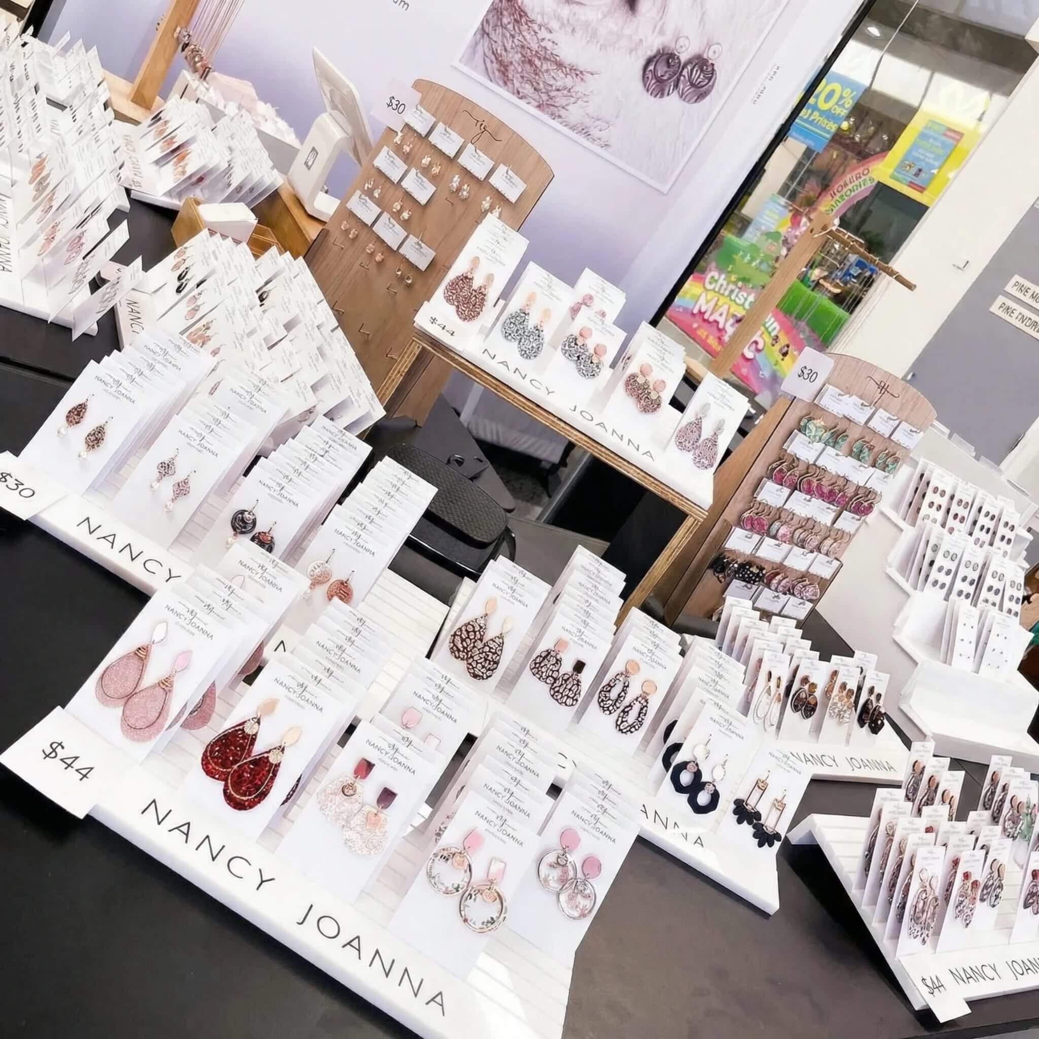 Glossy white acrylic earring card holder with sleek slots for organizing jewelry display cards in a boutique window.